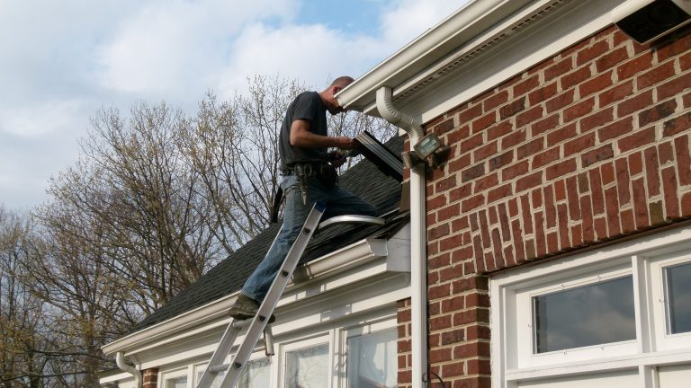 Professional installing gutter guards on home