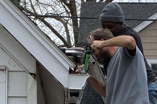 using a caulk gun to seal the end caps on new 6 inch gutters