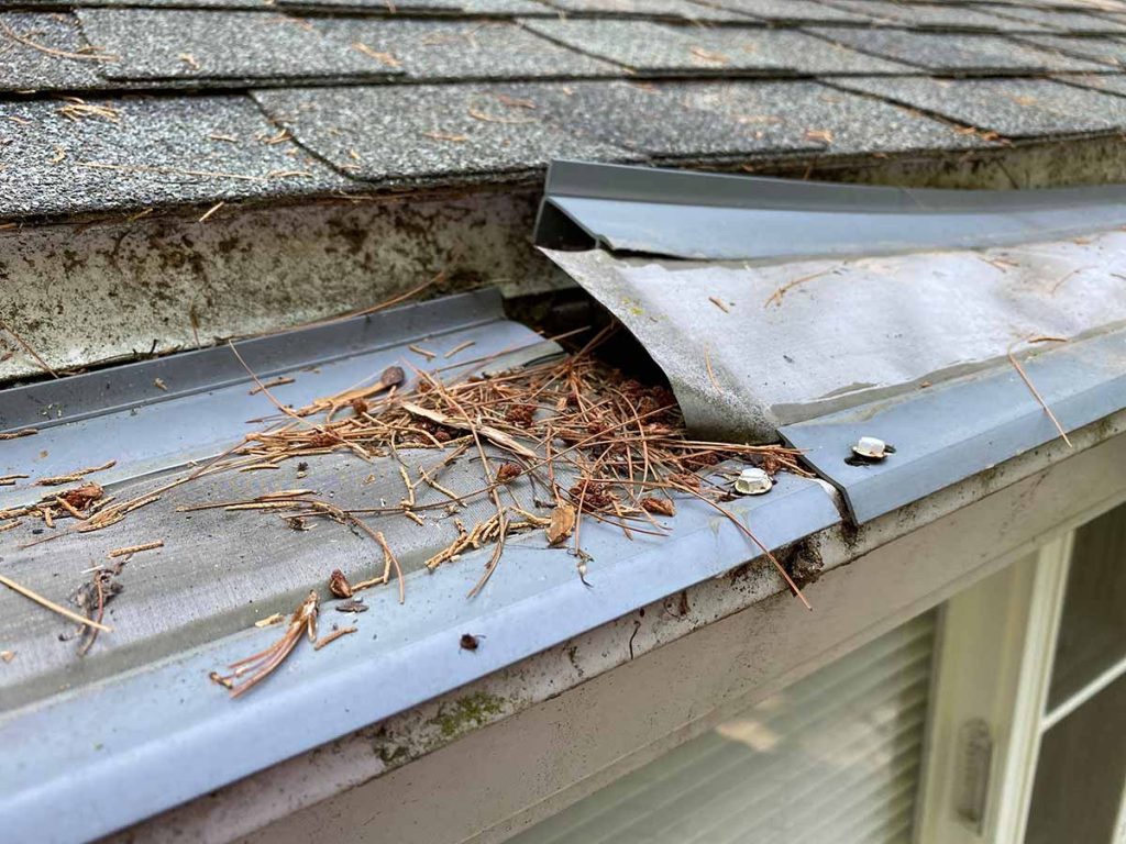 two end sections of leaffilter gutter guard that are warped. the right side has moved about 3 inches vertically and is at the same height as the roof shingles