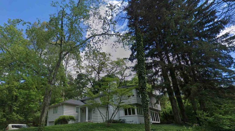 white clapboard sided home surrounded by spruce, oak and maple trees in Ann Arbor, Michigan