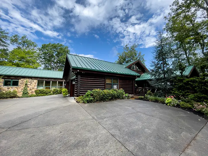 16-inch wide green snap lock standing seam metal roof on a log cabin style home in Townsend, Tennessee. Home also has 7" box gutters and micro mesh gutter guards installed by Gutter Guards Direct